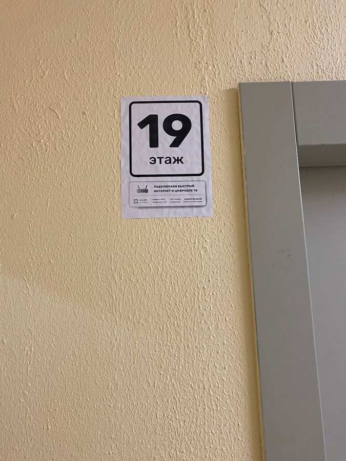Белая наклейка «19 этаж» у лифта